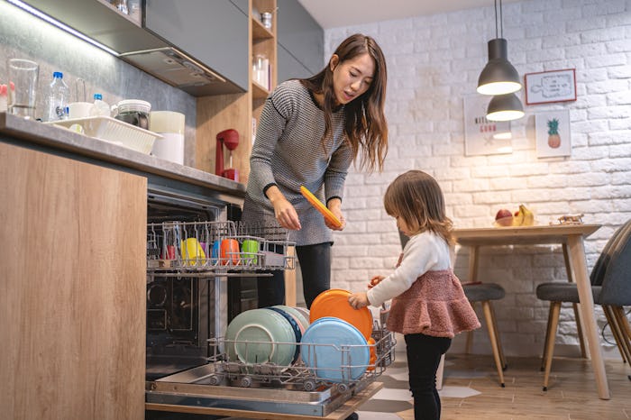 a little girl helping her mom unload the dishwasher