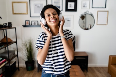 A young woman smiles while listening to music and working from home.