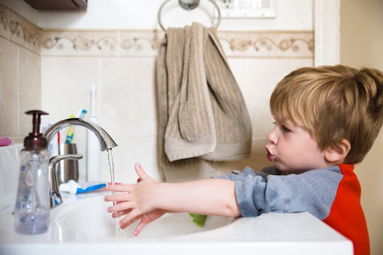 little boy washing hands in the bathroom sink