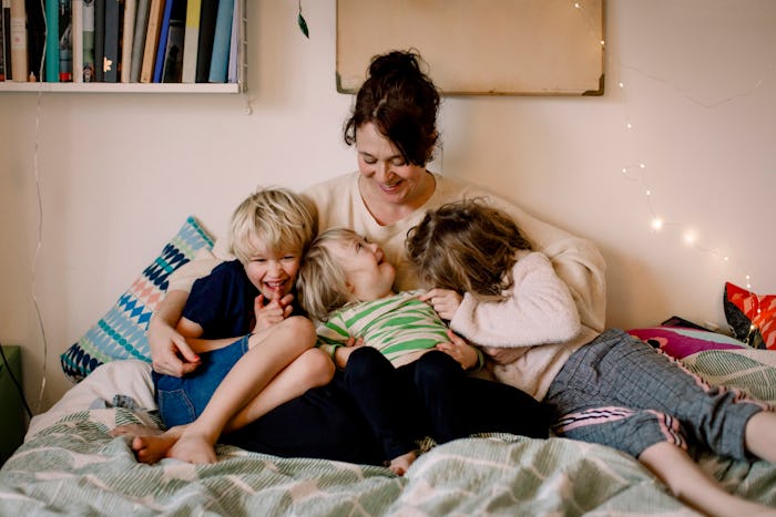 a mom and her kids snuggling on a bed