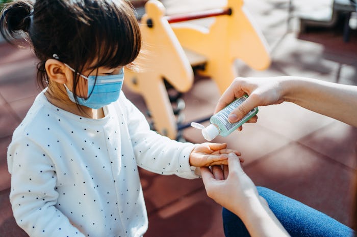 a teacher puts hand sanitizer on a little girl's hands in school