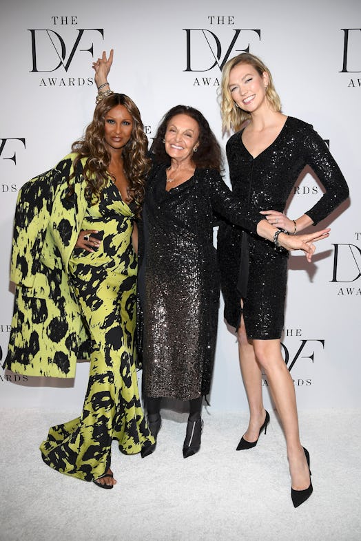 Diane Von Furstenberg in a black sequin dress posing with two models at the DVF awards