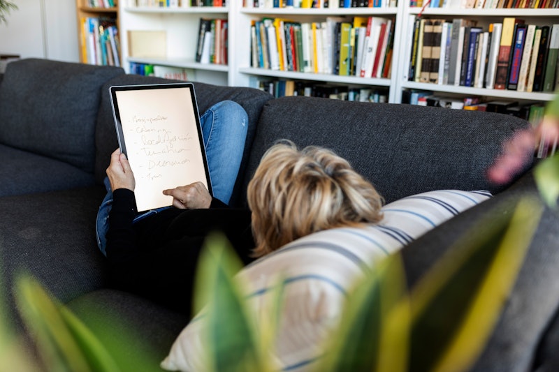 A woman writes on an ipad while lying on a couch. This article lists subtle signs of bipolar disorde...