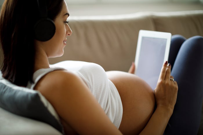 pregnant woman wearing headphones looking at ipad
