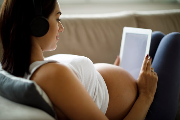 pregnant woman wearing headphones looking at ipad