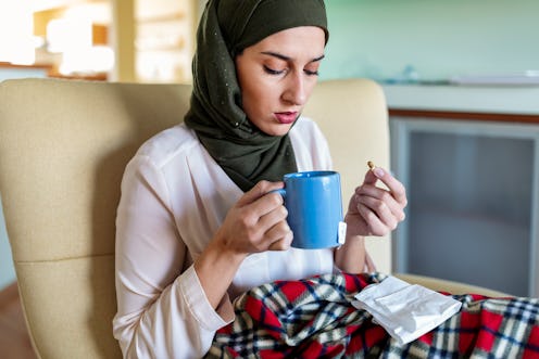 A woman takes medication with tea. This article details signs you might have a weak immune system