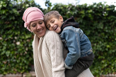 A mother going through cancer treatments laughs with her son.