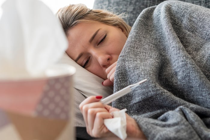 sick woman checking thermometer