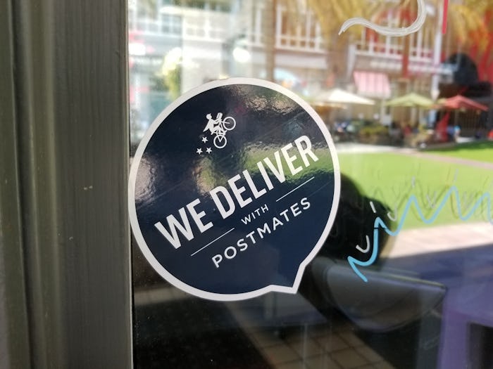 a postmates sticker in the window of a restaurant