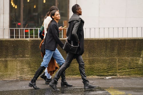 Three women walk down the street while wearing boots and jeans in spring