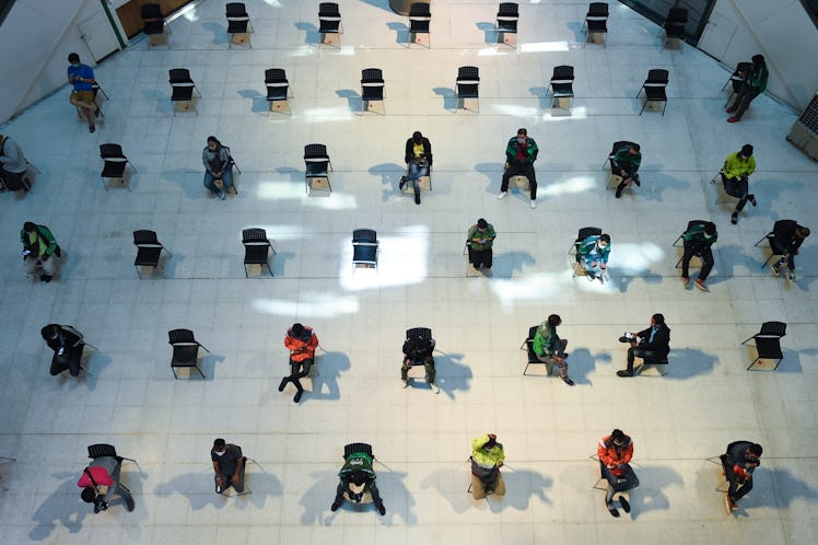 Food delivery drivers sit on chairs spaced apart for social distancing, as part of the effort to con...