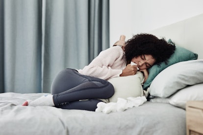 A woman surrounded by tissues in bed. If your spring allergies get worse at night, you're not alone
