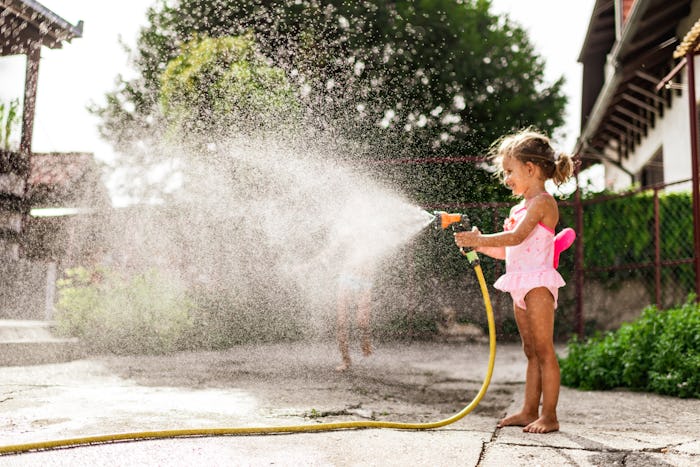 Playing with a water hose is a summer activity for kids at home. 