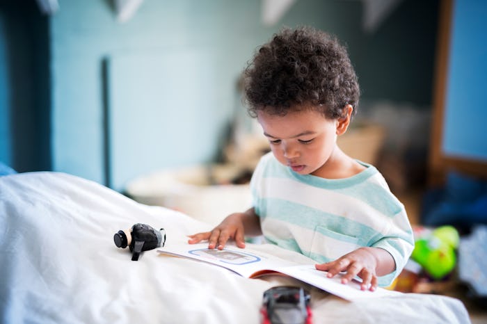 toddler boy looking at picture book in bedroom