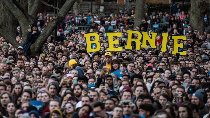 A large crowd holding large yellow letters that form 'BERNIE'