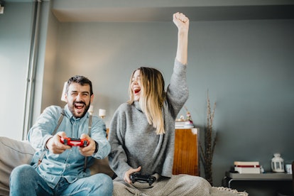 A young couple plays video games while hanging out at home.