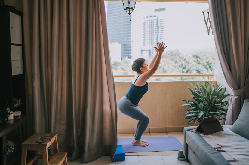 A woman does yoga on her balcony. Exercise in excess can disrupt periods. 