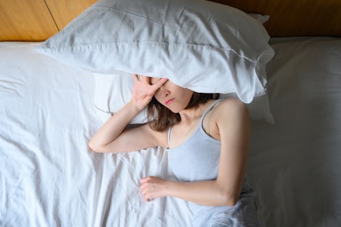 A woman is tired in bed with a pillow over her face. This article details 11 everyday things that ca...