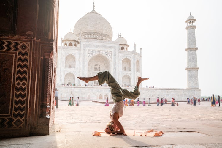 A young woman does a headstand while visiting the Taj Mahal.