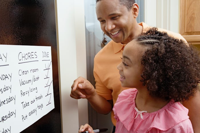 dad and daughter writing on chore chart