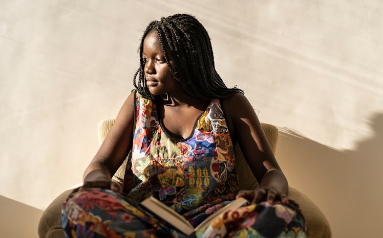 A young woman sits with a book in the sunlight.