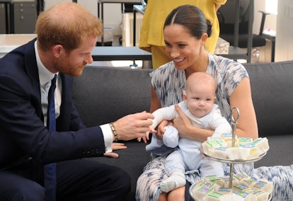 Prince Harry holds baby Archie's hand.