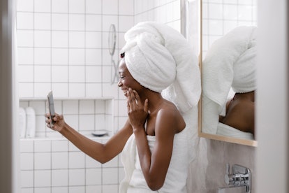 A young woman smiles in a towel while on video chat with her family.