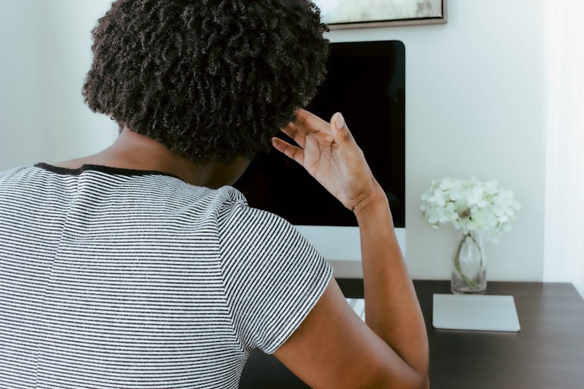 A woman looks at a screen with a headache. Screen time can increase headaches, because of glare, eye...