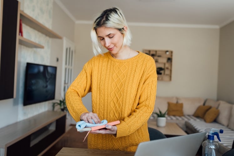 A young woman wipes down a journal while on video chat with her family.