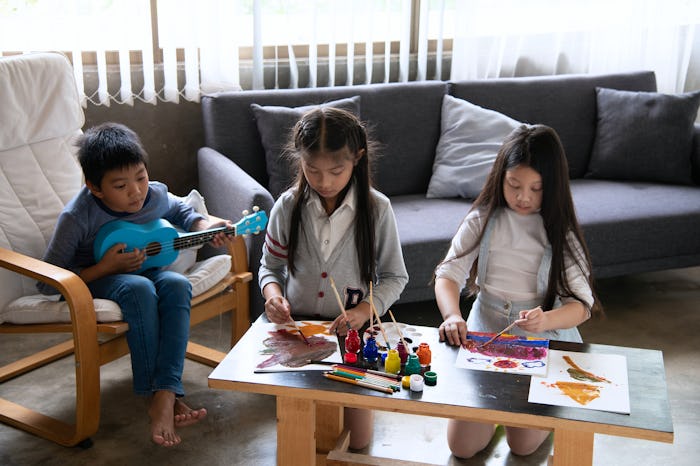 siblings doing art and music in living room