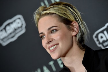 Kristen Stewart smiles on a red carpet with a messy, choppy, short pixie cut