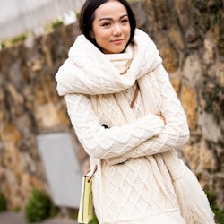 A woman in a cream-colored cardigan and matching scarf as her work from home attire