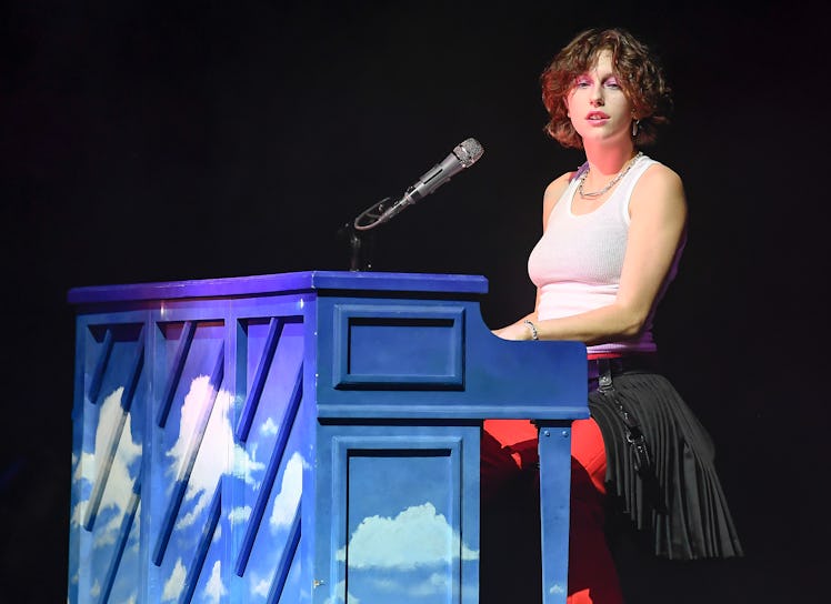 King Princess performs on stage styled in a white tank and a cute, short shag haircut