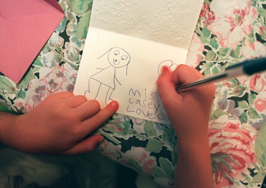 a child's hands writing a note to teacher