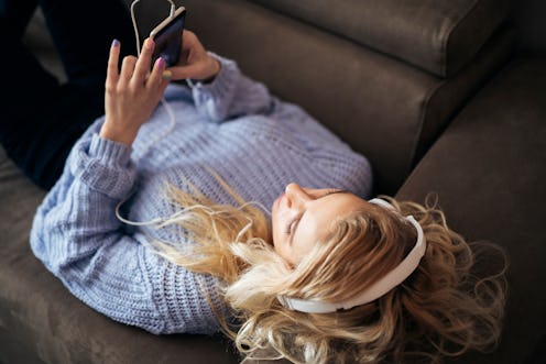 A woman lies on a couch scrolling on Instagram. Sharing old nostalgic photos for Instagram challenge...