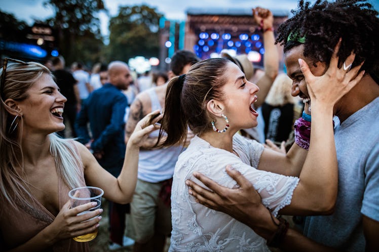 A young couple embraces and sings while at a music festival.