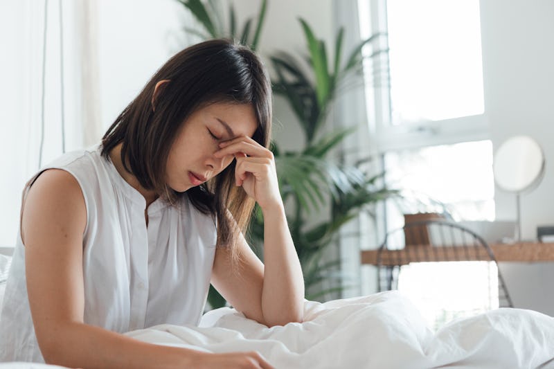 A woman with bed with a headache. Migraines appear most commonly in the mornings, according to speci...