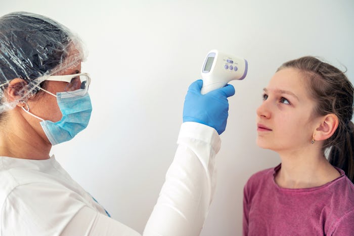 girl getting her temperature taken by pediatrician with mask for coronavirus