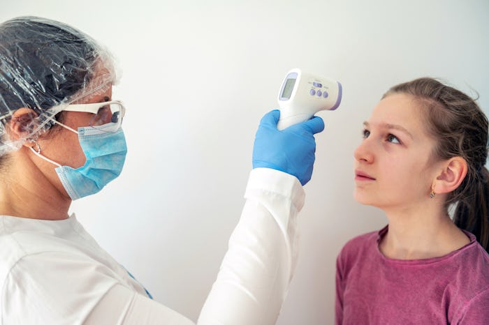 girl getting her temperature taken by pediatrician with mask for coronavirus