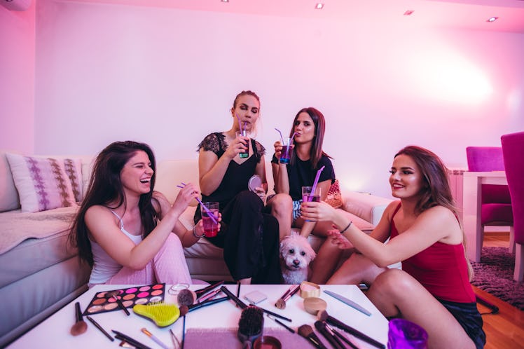 A group of friends sits in their living room with cocktails they made on TikTok, a dog, and makeup s...