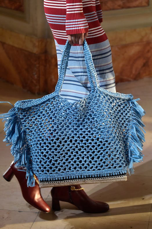 A closeup of a woman holding a blue woven bag