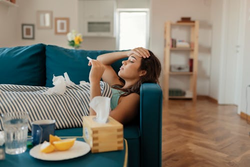 A woman checks her fever. Symptoms of coronavirus can include fever, shortness of breath, coughing, ...