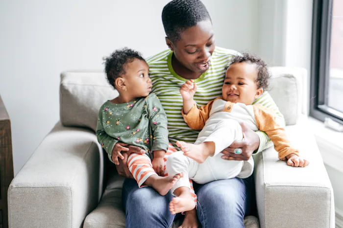 mom with twin babies on her lap sitting in chair