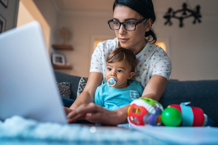 mom wearing glasses on laptop with baby