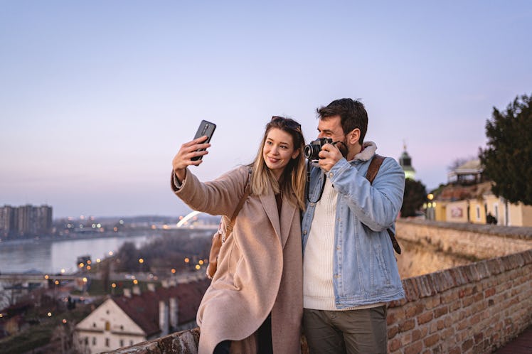 A young couple takes a selfie while traveling and exploring at sunset.