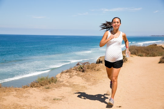 pregnant woman running wearing shorts by ocean