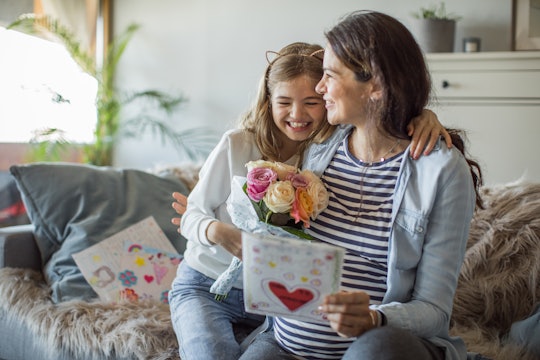 girl giving her mom a card and flowers on mother's day