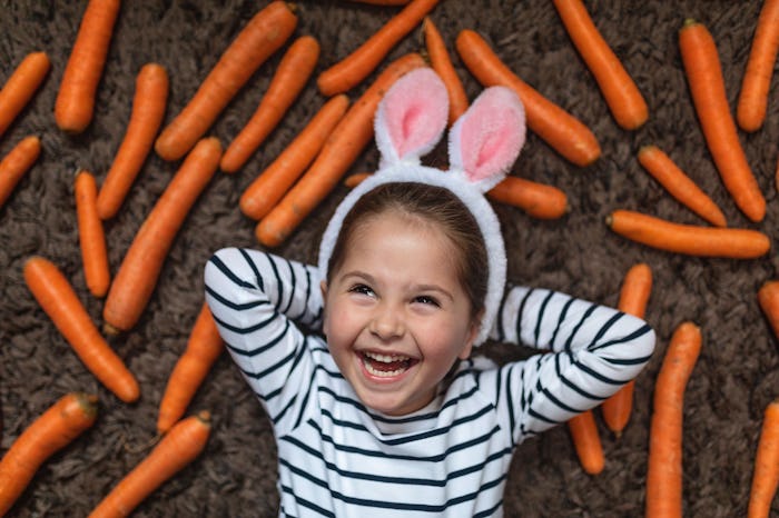 little girl wearing bunny ears with carrots in easter photo booth