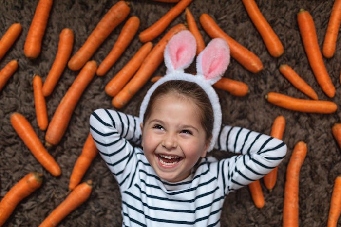 little girl wearing bunny ears with carrots in easter photo booth