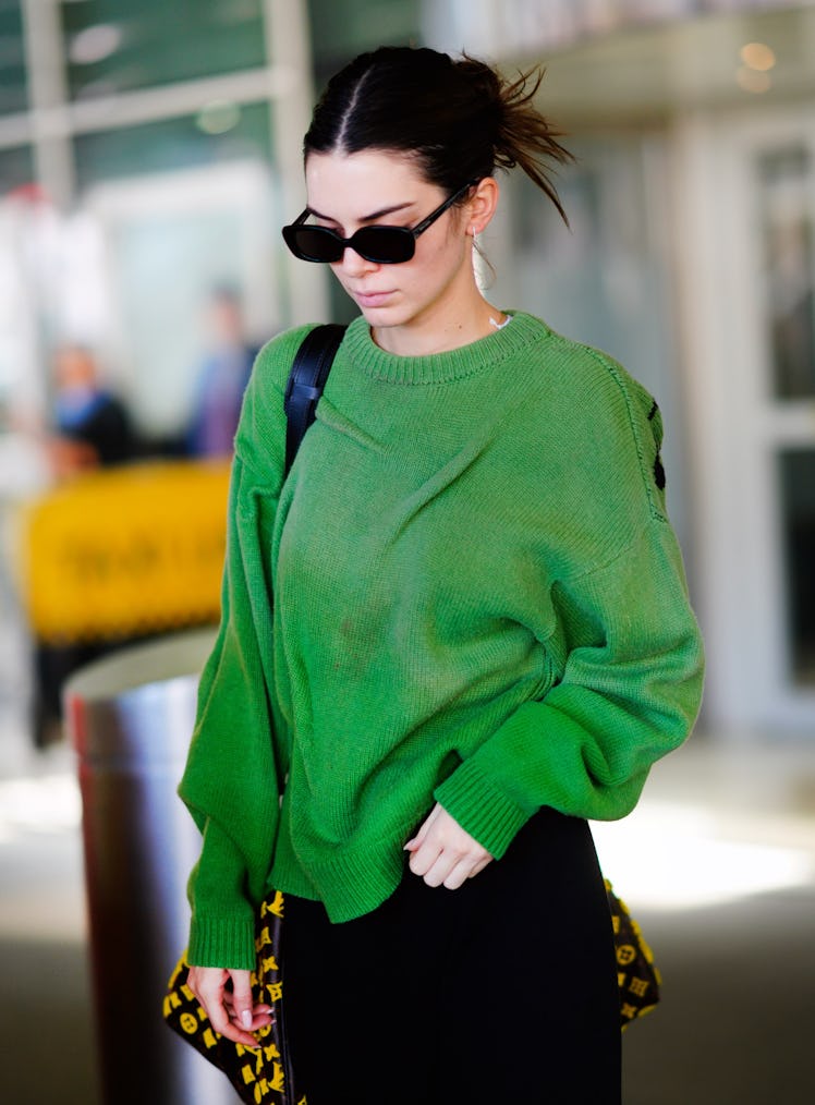 Kendall Jenner steps out in a green sweater and black shades.